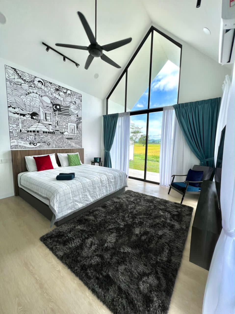 CYBER Suite at Ezu Isle Langkawi villa: king bed under a Malaysian flag mural, armchair and glass gable facing the padi and hills